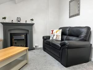 a black leather couch in a living room with a fireplace at Regent House in Scarborough