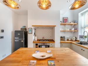 a kitchen with a wooden table and a refrigerator at Pebble Cottage in Cullercoats