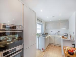 Una cocina con gabinetes blancos y un refrigerador de acero inoxidable. en Swn Y Mor, en Trearddur