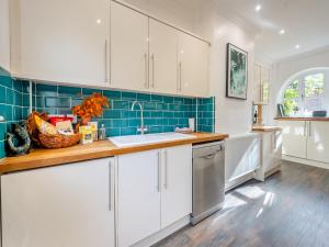 eine Küche mit weißen Schränken und blauen Fliesen in der Unterkunft Blofield Cottage - Uk48095 in Norwich + 17 Fotos