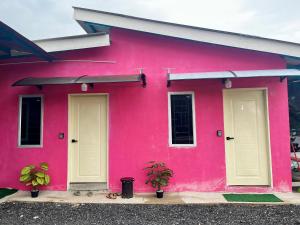 a pink house with two doors and two plants at Avina's Family Room in Setiu