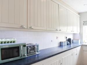 a kitchen with white cabinets and a microwave on a counter at Och Moo At Number 47 in Seahouses