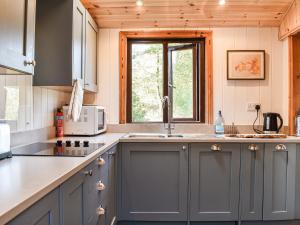 a kitchen with blue cabinets and a window at The Cottage At Dockens Water in Fritham