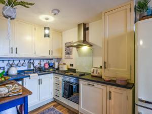 a kitchen with white cabinets and a stove top oven at The Cwtch in Ludlow