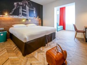 a hotel room with a large bed and a brown purse at ibis Styles Saumur Gare Centre in Saumur +100 photos
