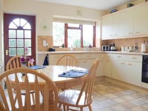 a kitchen with a wooden table and chairs and a table and a window at The Byre in Pencombe