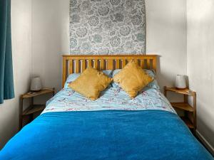 a bedroom with a blue bed with two yellow pillows at Osokozy Cottage in Shrawley