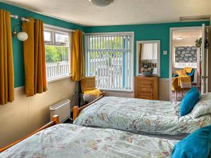two beds in a room with green walls and windows at Osokozy Cottage in Shrawley
