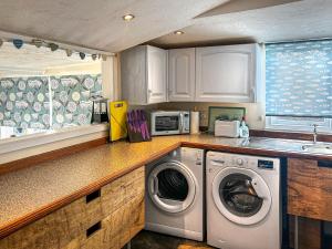 a kitchen with a washing machine and a microwave at Osokozy Cottage in Shrawley