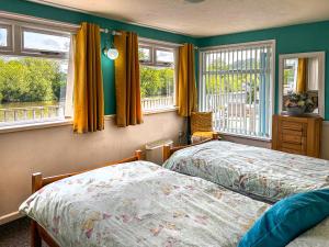 two beds in a bedroom with two windows at Osokozy Cottage in Shrawley +3 photos