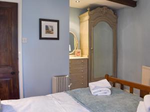 a bedroom with a bed and a dresser and a mirror at Letterbox Cottage in Far Sawrey