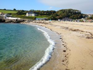 a beach with a group of people walking on the sand at Hazel Cottage in Budock Water +1 photo