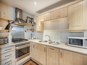 Una cocina con armarios de madera, fregadero y microondas. en The Forge - Uk44517, en North Thoresby