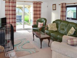 a living room with a green leather couch and a chair at Angerton Cottage in Kirklinton