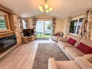 a living room with a couch and a flat screen tv at Lovely Dog Friendly Caravan For Hire At California Cliffs, Norfolk Ref 50027K in Great Yarmouth