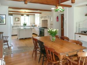 Una cocina con una mesa y sillas de madera. en Dove Cote House, en Westleigh
