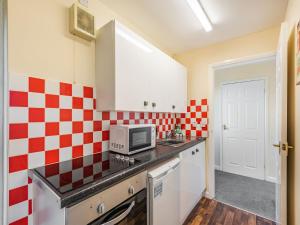a kitchen with red and white checkered tiles on the wall at Rainbow Bungalow 1 - Uk39809 in Chapel Saint Leonards