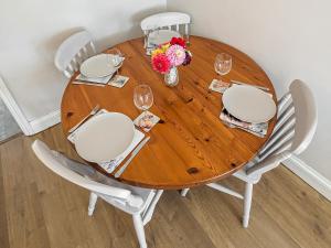 a wooden dining room table with white chairs and flowers at Pixies Wood Cottage in Ludham