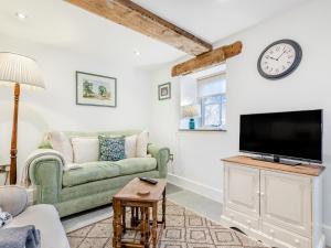 a living room with a green couch and a tv at Clarence Cottage - Uk47494 in Waterfall