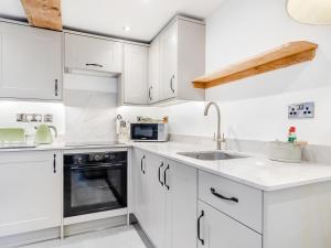 a white kitchen with white cabinets and a sink at Clarence Cottage - Uk47494 in Waterfall +8 photos