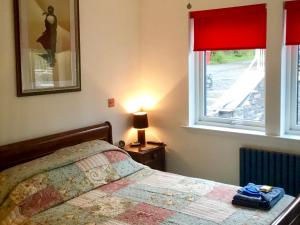 a bedroom with a bed and a window with red curtains at Tidereach - Otters View - Uk12269 in Connel +11 photos