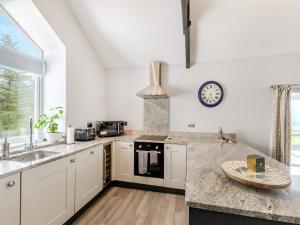 a kitchen with white cabinets and a clock on the wall at Bracken Cottage in Alston