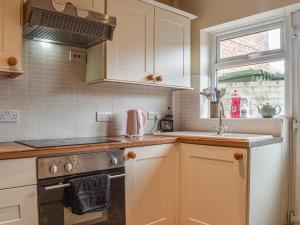 a kitchen with white cabinets and a sink at Sea Dog Cottage in Scarborough