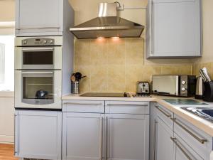 eine Küche mit weißen Schränken und einem Herd mit Backofen in der Unterkunft The Cottage - Uk35177 in Abbots Bickington