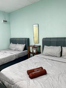 a hotel room with two beds with a pillow on the bed at Avina's Family Room in Setiu