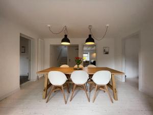 a dining room with a wooden table and white chairs at Lower Hilton Cottage in Culrain