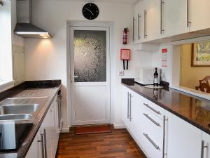 a kitchen with white cabinets and a door with a clock at Nantucket House in Misterton