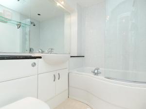 a white bathroom with a tub and a sink at Beachlands in Llanelli