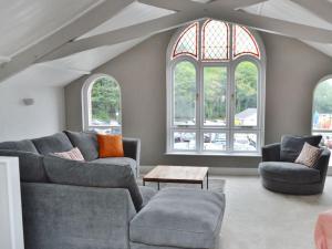 een woonkamer met een bank, 2 stoelen en ramen bij St Monicas in Fowey