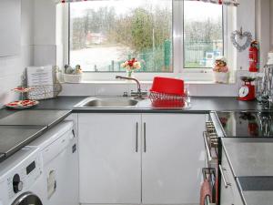 a kitchen with white cabinets and a sink and a window at Chainbridge Cottage in Whitby