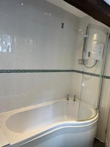 a white bath tub in a white tiled bathroom at Dunsdale Lodge in Frodsham +6 photos