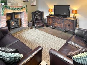 a living room with leather furniture and a fireplace at Old Kielder Castle Cottage in Kielder