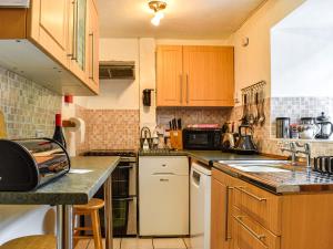 a small kitchen with wooden cabinets and appliances at Church House Cottage in Ulpha