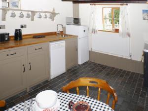 een keuken met een tafel en een wastafel en een tafel en een tafel bij Garden Cottage in Onecote