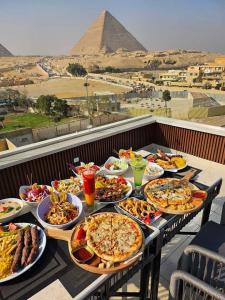 a table with many plates of food and the pyramids at Pyramids Acme Inn in Nazlet el-Sîsi