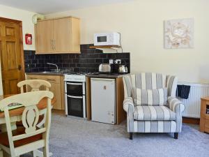 a kitchen with a chair and a stove top oven at Percheron Cottage in Sewerby