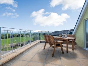 a patio with a wooden table and chairs on a balcony at Penceunant in Penuwch