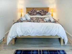 a bedroom with a large bed with white sheets and pillows at Hillview Cottage in Aberfeldy