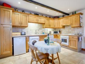 a kitchen with wooden cabinets and a table and chairs at Lintel Barn - E5253 in Runcton Holme +14 photos