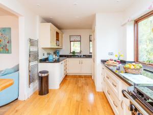 a kitchen with white cabinets and a wooden floor at Wagtails in Milverton +23 photos