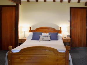 a bedroom with a large wooden bed with blue pillows at Meadowsweet Cottage - E1496 in Scalby +10 photos