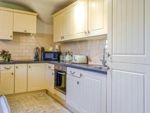 a kitchen with white cabinets and a sink at Millstream - Uk45183 in Penton +22 photos