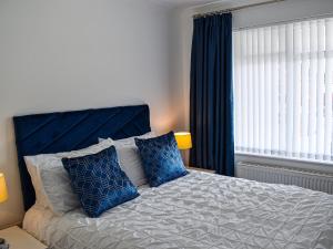 a bedroom with a bed with blue curtains and a window at Coleridge Lodge in Thornton
