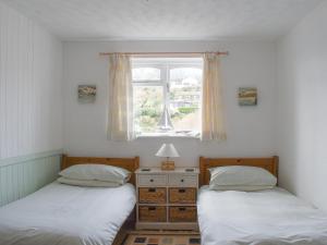 two twin beds in a room with a window at Garden Cottage - Uk30590 in Polperro