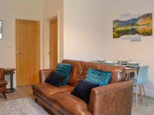 a living room with a brown leather couch and a table at Howbeck Cottage in Hesket Newmarket