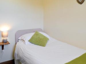 a bedroom with a white bed with a green pillow at Clydesdale Cottage in Sewerby +6 photos